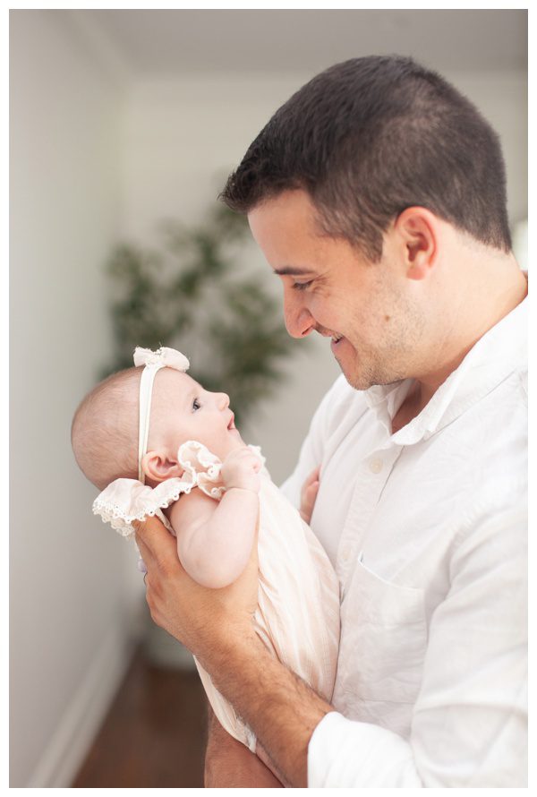 Dad smiling at baby girl in Stamford CT home for lifestyle newborn session