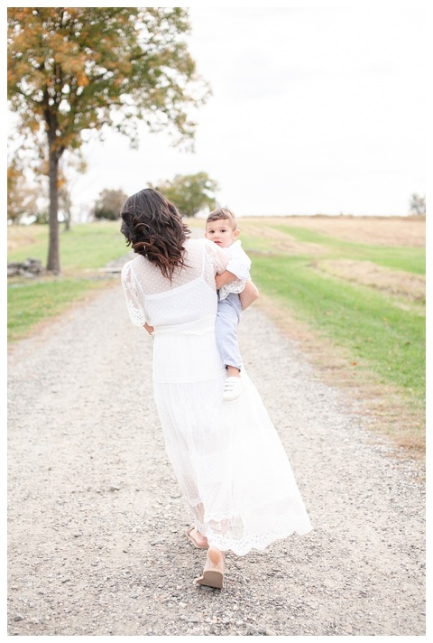 mom walking while holding son during fall family portraits