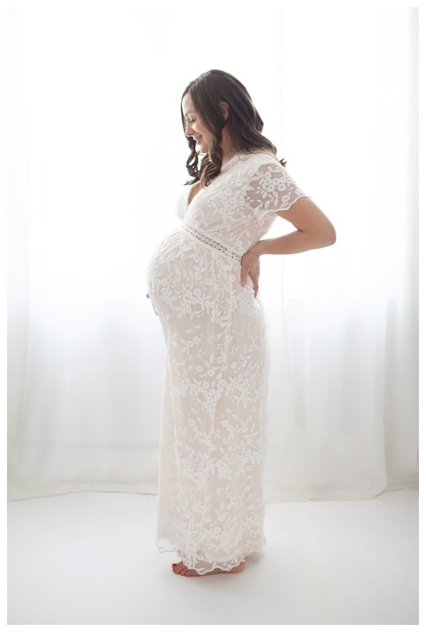 Gorgeous pregnant mom wearing white lace gown.