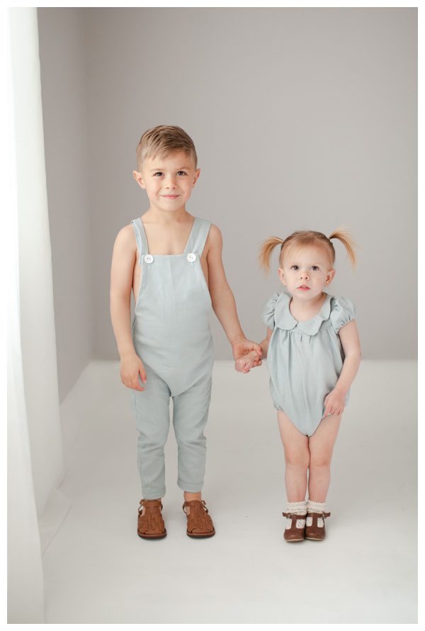 Siblings holding hands and looking at the camera for photos