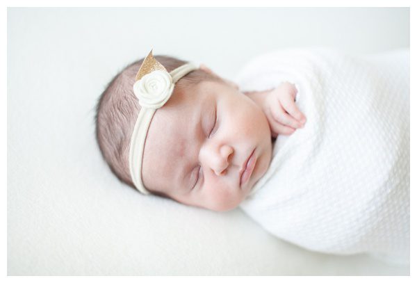 Sleeping newborn with hand sticking out of swaddle