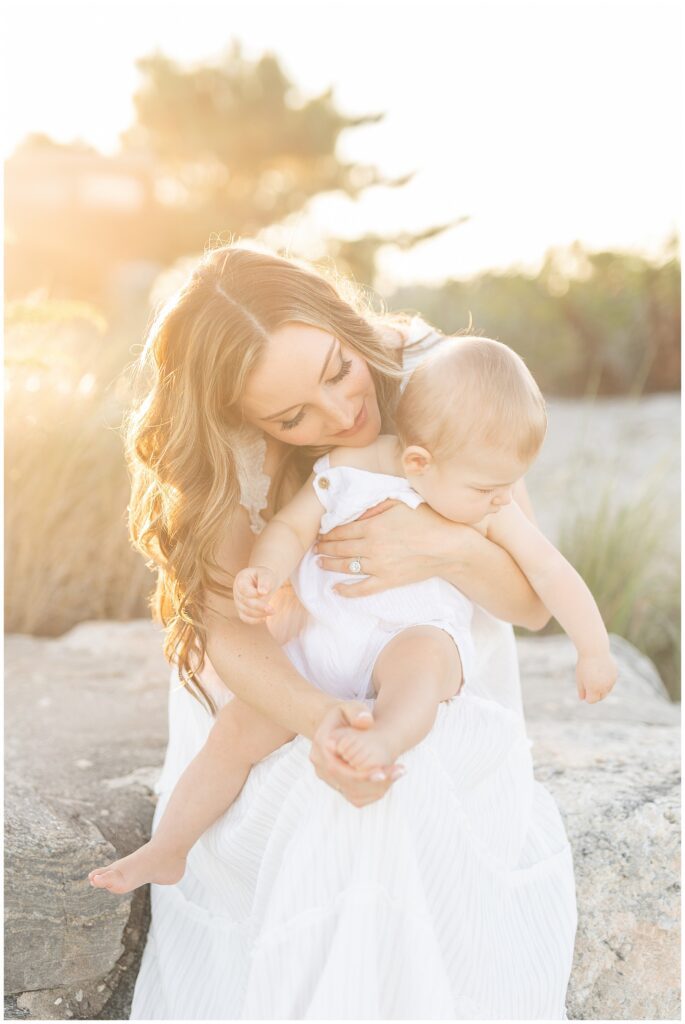 Golden hour beach portraits for the family in Greenwich CT. Forty Seven Moments Photographer captures mom and her one year old sun in the golden light of sunset. Light and airy photography family photos on the beach.